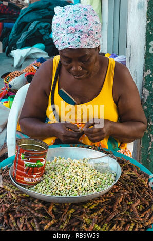 06-01-2019 Santo Domingo, Dominikanische Republik. Schwarz senior Frau alleine öffnen Hülsen bei ihren Markt am Arbeitsplatz Stockfoto