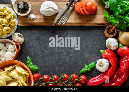 Zutaten für italienische Küche. Frisches Gemüse, Mozzarella, Kräuter und Nudeln in dunklen Stein Hintergrund. Stockfoto