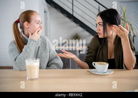Porträt eines Mädchens erzählen, Geheimnisse zu ihrem Staunen Freund sitzen in einem Café in der Mittagspause Stockfoto