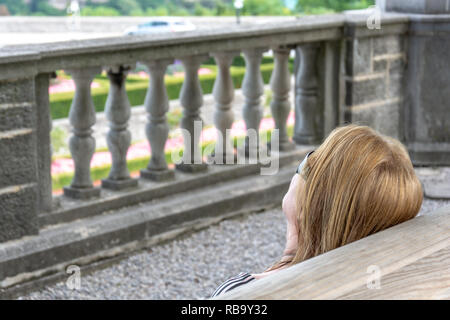 Die Vision eines "eine blonde Frau mit Sonnenbrille vor einem konkreten Dekorative niedrige Mauer Stockfoto