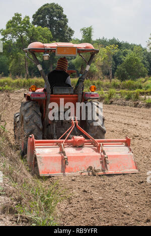 Thailändische Bauern sind mit einem Traktor der Boden für den Anbau von Reis vorzubereiten. Stockfoto