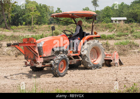 Thailändische Bauern sind mit einem Traktor der Boden für den Anbau von Reis vorzubereiten. Stockfoto