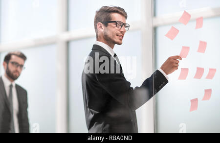 Mitarbeiter liest klebrig - Hinweise auf Glas. Stockfoto