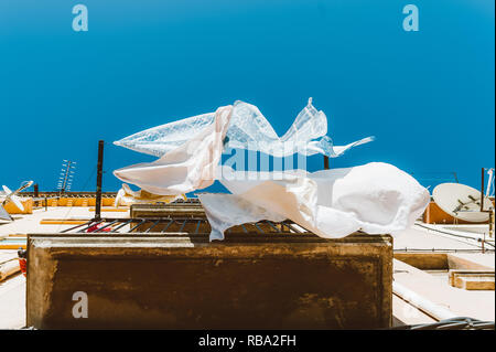 Eindrucksvolle Bild der sauberen, weißen Bettwäsche fließend und tanzen im Wind im Sommer Tag gegen den strahlend blauen Himmel Stockfoto