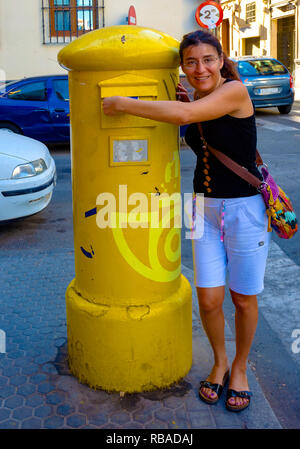 Junge Frau steckt einen Brief in ein Postfach in Spanien Stockfoto