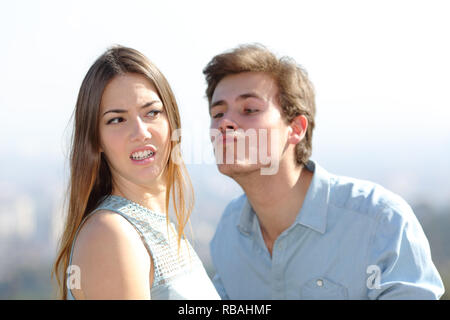 Wütende Frau lehnt einen Freund Kuss an einem sonnigen Tag Stockfoto