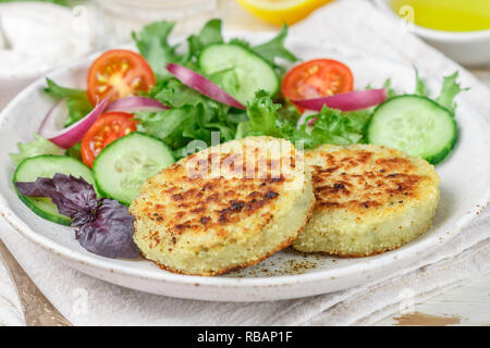 Vegetarische gesunde Gemüse koteletts von Kohl, Kartoffeln, Zucchini, Zwiebeln und Grüns. Mit Salat, Tomaten- und Gurkensalat und Pastetchen Platte Stockfoto