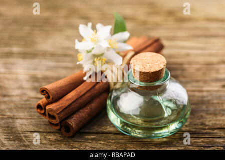Wesentliche Massage Öl mit Jasmin Blume und Zimt Aroma auf rustikalen Holzmöbeln Hintergrund. Natural Spa und Wellness Aromatherapie Behandlung immer noch Leben. Stockfoto