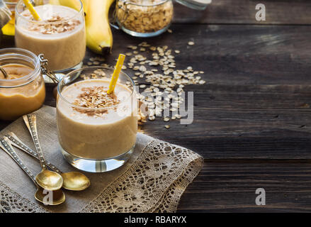 Frische hausgemachte Ernährung Smoothie mit Banane, Haferflocken und Erdnußbutter auf rustikalen Holzmöbeln Hintergrund mit Zutaten. Gesundes Frühstück. Stockfoto