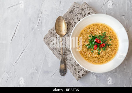 Hausgemachte Linsensuppe in der Schüssel auf grauem Beton Hintergrund. Gesunde vegetarische Nahrung. Stockfoto