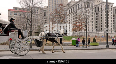 Tagsüber macht sich ein Reiter in einer Pferdekutsche über den Public Square im Zentrum von Cleveland, Ohio, während der Winterferien auf den Weg. Stockfoto