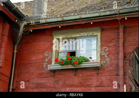 Österreichischen Haus Fenster mit kunstvollem Design und rote Geranie Pflanzen im Fenster Stockfoto