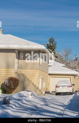 Schnee bedeckt Wohn- Einfahrt mit weißen Auto geparkt ist Stockfoto