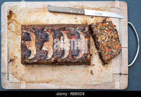 Vegan Mutter braten/Mutter Brot auf einem Holzbrett mit einem Vintage Küchen Messer von oben. Großbritannien Stockfoto