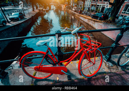 Symbole von Amsterdam: rotes Fahrrad auf einer Brücke, Niederlande geparkt. Reisen, Romantik, Urlaub. Kultur Konzept Stockfoto