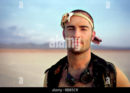 Porträt einer abenteuerlichen jungen Mann mit dem Stirnband aus Stoff, während in der Wüste. Stockfoto