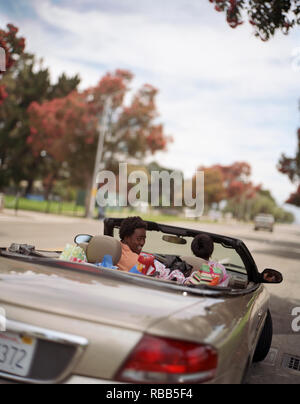 Porträt eines lächelnden jungen Mann über die Schulter schauen, während in einem Cabrio sitzt mit seiner Freundin. Stockfoto