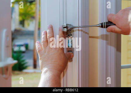 Nahaufnahme eines professionellen Bauschlosser installieren oder Reparieren eines neuen deadbolt Verschluss auf eine Haustür mit der Innenseite interne Teile des Schließmechanismus sichtbar. Stockfoto