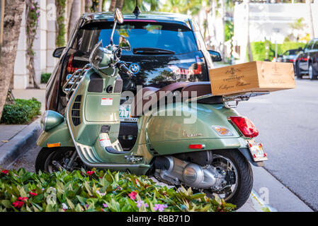 Vespa Motorroller mit toskanischer Wein Kiste außerhalb von Saks Fifth Avenue an der Esplanade auf der Worth Avenue in Palm Beach, Florida. (USA) Stockfoto