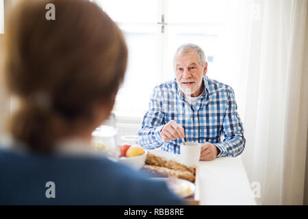 Ein älteres Paar am Tisch zu Hause sitzen, frühstücken. Stockfoto