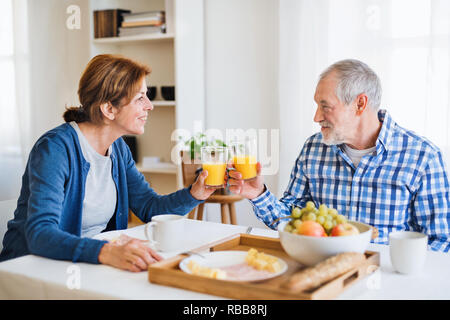 Ein älteres Paar am Tisch zu Hause sitzen, frühstücken. Stockfoto
