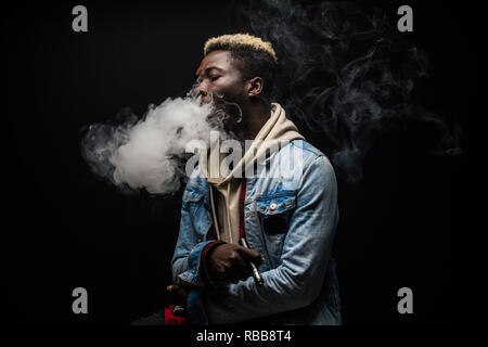 Mann rauchen oder vaping E-Cig oder elektronische Zigarette Holding ein Mod mit viel Wolken Stockfoto