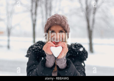 Lächelnde Frau mit Schnee in Herzform. Stockfoto