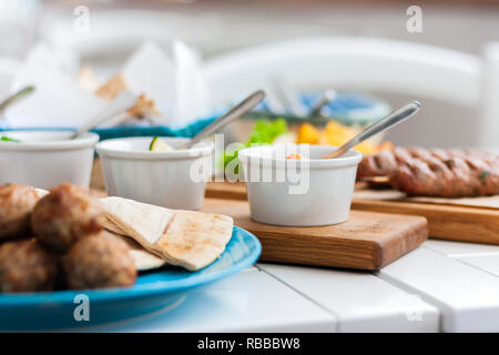 Gebratene Fleischbällchen mit weißer Soße und flache Kuchen - traditionelle griechische Mittagessen auf einem blauen Platte in einem Restaurant Stockfoto