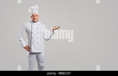 Koch in eine weiße Uniform macht eine Geste. Stockfoto