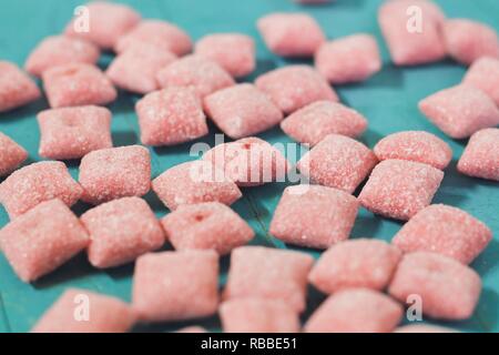 Rote Farbtöne square Zucker Süßigkeiten. Bonbons liegen auf der Holzoberfläche des Blauen otyaenok. Sehr lecker und Süßigkeiten. Stockfoto