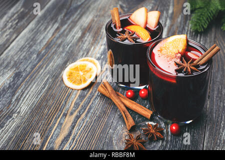 Weihnachten Glühwein mit Gewürzen, Orangenscheiben, Zimtstangen und Tannenzweigen auf hölzernen Tisch. Traditionelle Getränk auf Winterurlaub. Im rustikalen Stil. Stockfoto