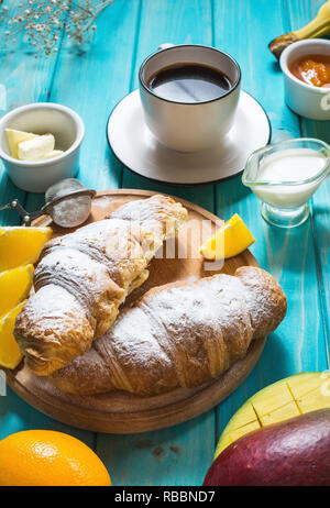 Frühstück serviert mit Kaffee, Orangensaft, Croissants und Obst auf Blau Holz Hintergrund Stockfoto