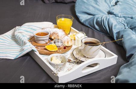 Frühstück im Bett, mit Kaffee, Croissants und Orangensaft auf Weiß Fach. Stockfoto
