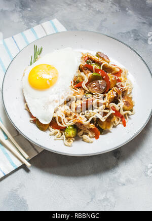 Udon unter Rühren braten, Nudeln mit Huhn auf konkreten Hintergrund. Stockfoto