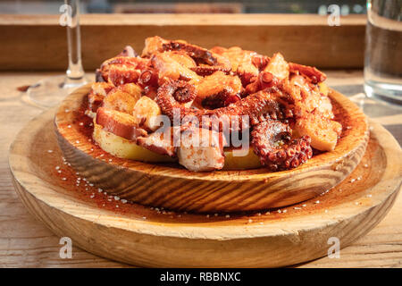 Ein Foto von pulpo a la Gallega, traditionelle Spanische octopus Teller, in der typische hölzerne Schüssel serviert. Stockfoto