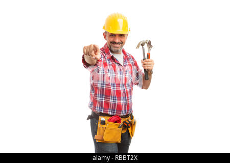 Lächelnd Builder zeigen auf Kamera mit Zeigefinger halten Hammer und Schraubenschlüssel in der Hand isoliert auf weißem Stockfoto
