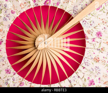 Flach. Traditionelle Ventilator mit fernöstlichen Motiv auf einem roten Hintergrund Nahaufnahme Stockfoto