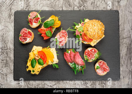 Verschiedene Arten von bunten Sandwiches auf Schwarze Schiefertafel Hintergrund von oben. Starter oder Vorspeise - Flachbild Komposition legen. Stockfoto