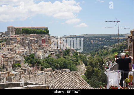 Blick über die Dächer von Ragusa auf Sizilien, Italien mit einer Frau auf einem Balkon Aufhängen der Wäsche Stockfoto