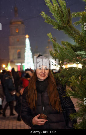 Junge ukrainische Frau in Wolle hat genießt Urlaub Geist am Weihnachtsmarkt auf StSofia Square in Kiew von Weihnachtsbaum und vielen Menschen aus der Ukraine Stockfoto