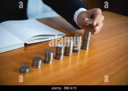 Geschäftsmann nimmt Münzen auf den Tisch und zählt Geld. Geschäftskonzept. Stockfoto