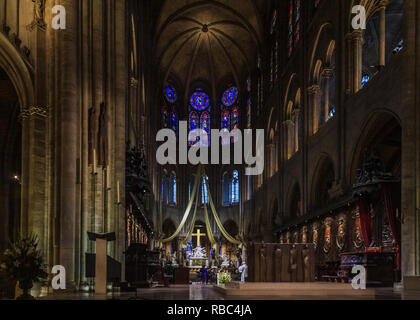 Blick auf die Kanzel, der Altar und das Kreuz der Notre Dame de Paris Kathedrale mit der buntglasfenster an der hinteren Wand während einer Messe in Stockfoto