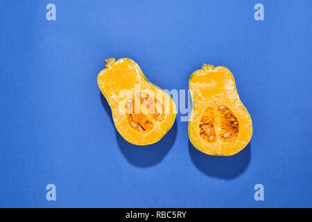 Die beiden Hälften des Ripe butternut Kürbis Kürbis auf blauem Hintergrund. Orange Kürbis mit einem Schwanz. Close-up Stockfoto