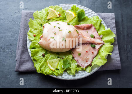 Gekochte ganze Kalmare auf einem Teller. Fisch und Meeresfrüchte Stockfoto