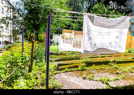 Viele hängende Kleidung Zeilen im Sommer Garten mit bunten T-Shirts die Trocknung auf Rack in der Ukraine oder Russland von sowjetischen Apartment Gebäuden Stockfoto