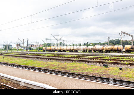 Riwne, Ukraine - 25. Juli 2018: Eisenbahn Eisenbahn Schienen mit der Bahn Straße Straße in der westlichen Ukraine, Stromleitungen und industriellen Ladetanks Stockfoto