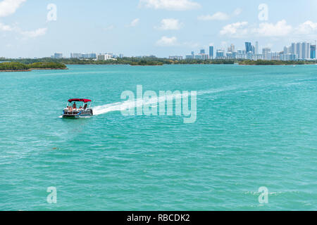 Bal Harbour, USA - Mai 8, 2018: Boot in Miami Florida mit Hellgrün türkis Meer Biscayne Bay Intracoastal Wasser und Stadtbild Skyline von Sonnig Stockfoto