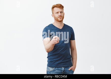 Wir brauchen Sie, Sie uns. Ernst - auf der Suche schöne und selbstbewusste Reife bärtige rothaarige Mann in casual blaues T-Shirt, zeigen auf Kamera mit Zeigefinger ernst und Strenge über graue Wand Stockfoto