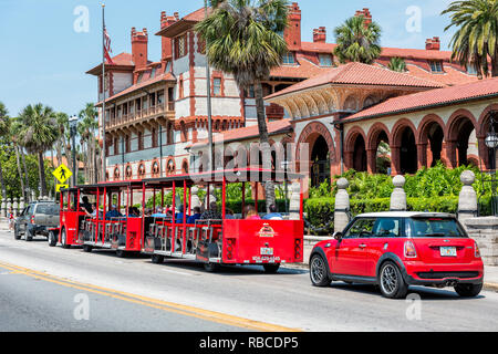 St. Augustine, USA - 10. Mai 2018: Flagler College mit Florida Architektur, berühmte Statue in historische Stadt und Roten Zug Trolley Tour Guide Straßenbahn Stockfoto
