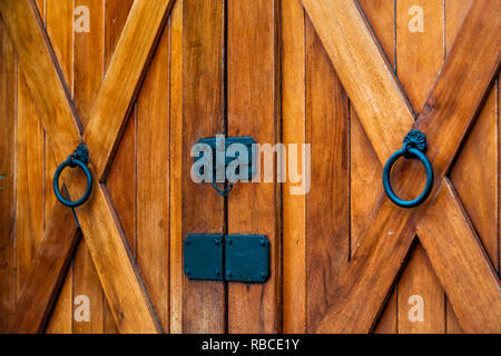 Bauernhof rustikales Haus Eingang mit braun-orange Farbe von Holz- oder Holz Tür und schwarzer Griff abstrakte Closeup auf Charleston in South Carolina mit Kreuz Stockfoto